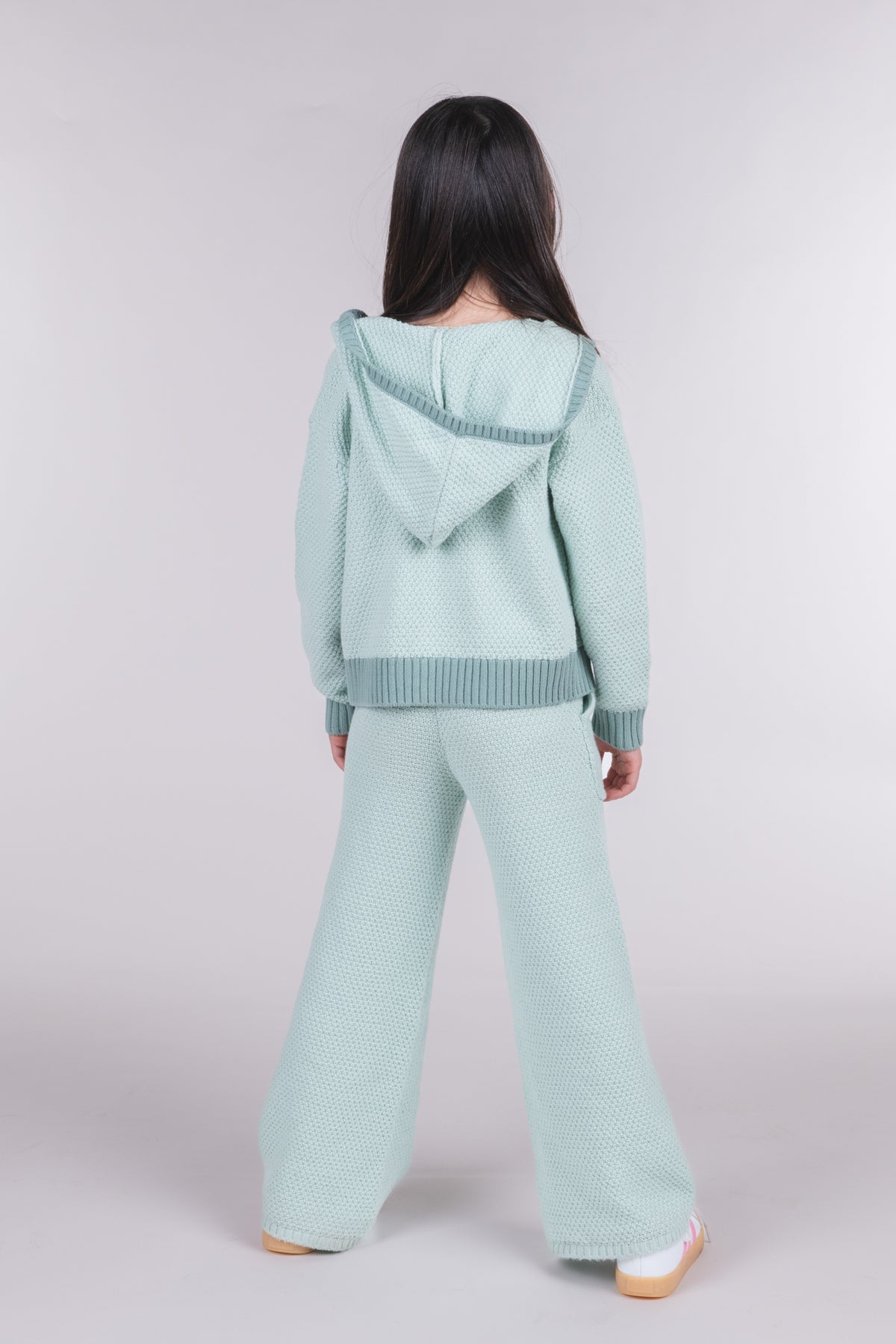 Back view of tween girl wearing seafoam green knit sweater pants and hooded cardigan