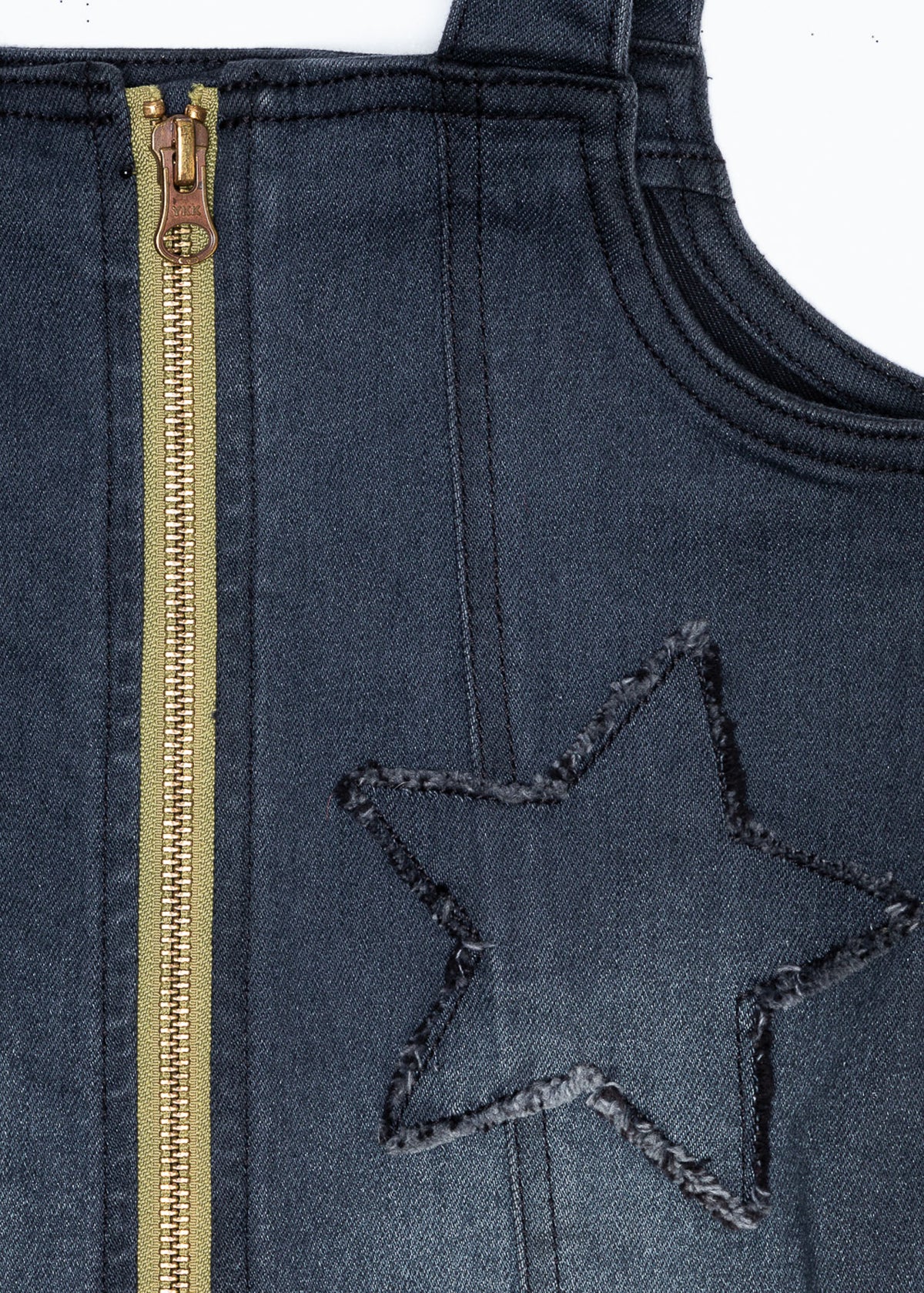 Close-up of denim jumper dress fabric with gold zipper and star patch