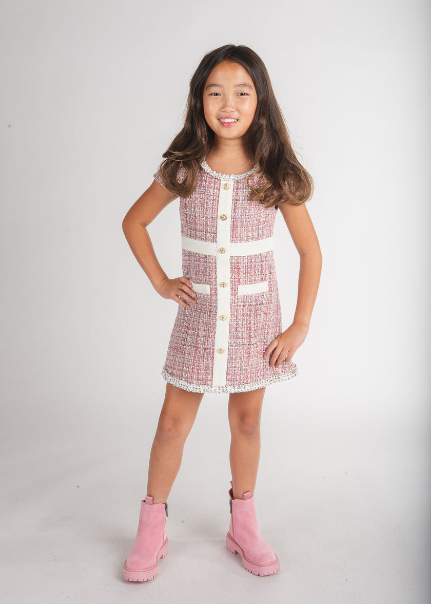 Tween girl wearing a pink tweed button-front dress with white trim and pink boots