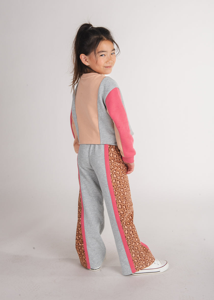 Tween girl wearing grey sweatpants with pink and leopard-print side stripes