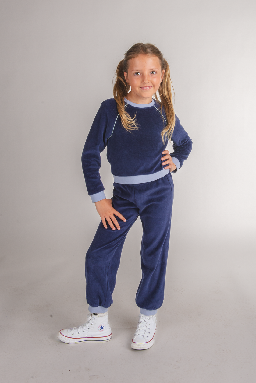 Tween girl wearing a navy velour sweatshirt top with light blue trim and matching pants