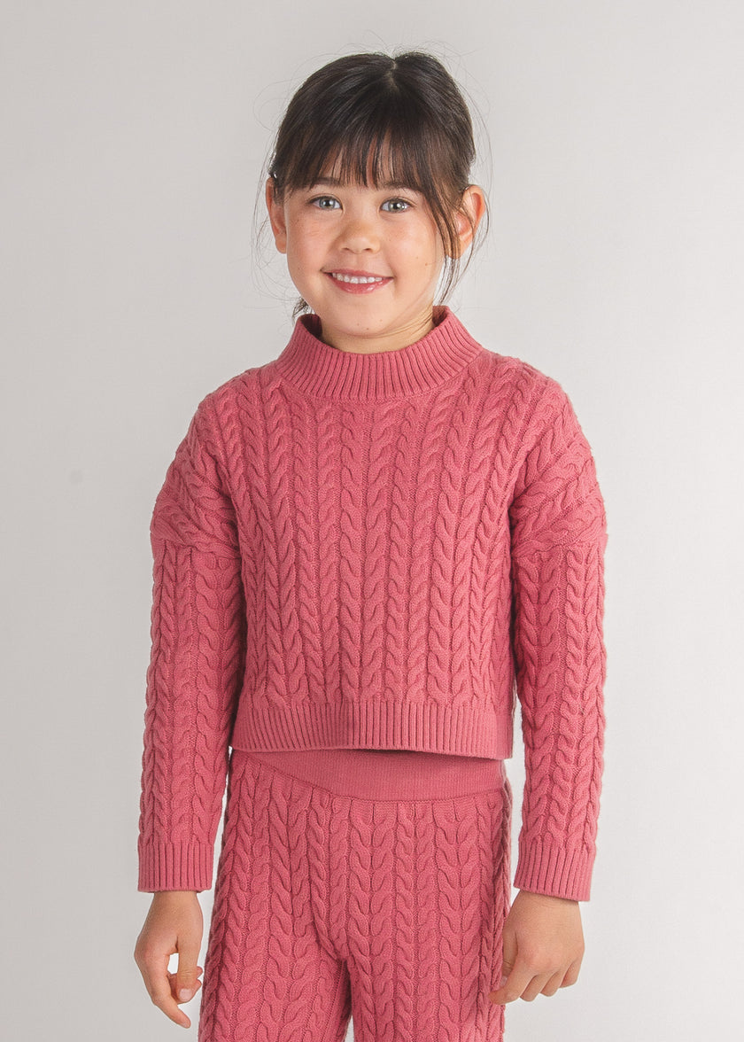 Tween girl wears a pink cable-knit sweater with matching pants