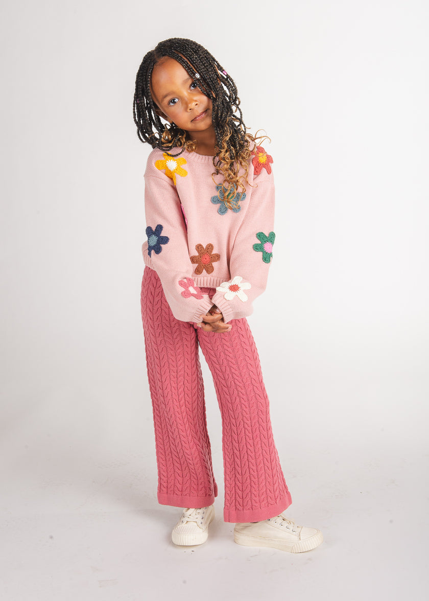 Tween girl wearing rose cable-knit wide-leg pants with a pink floral-appliqué sweater and white sneakers