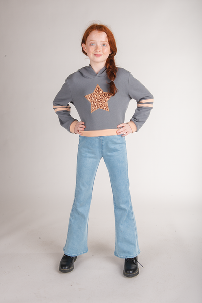 Tween girl wearing a gray hoodie with a leopard-print star patch and peach trim