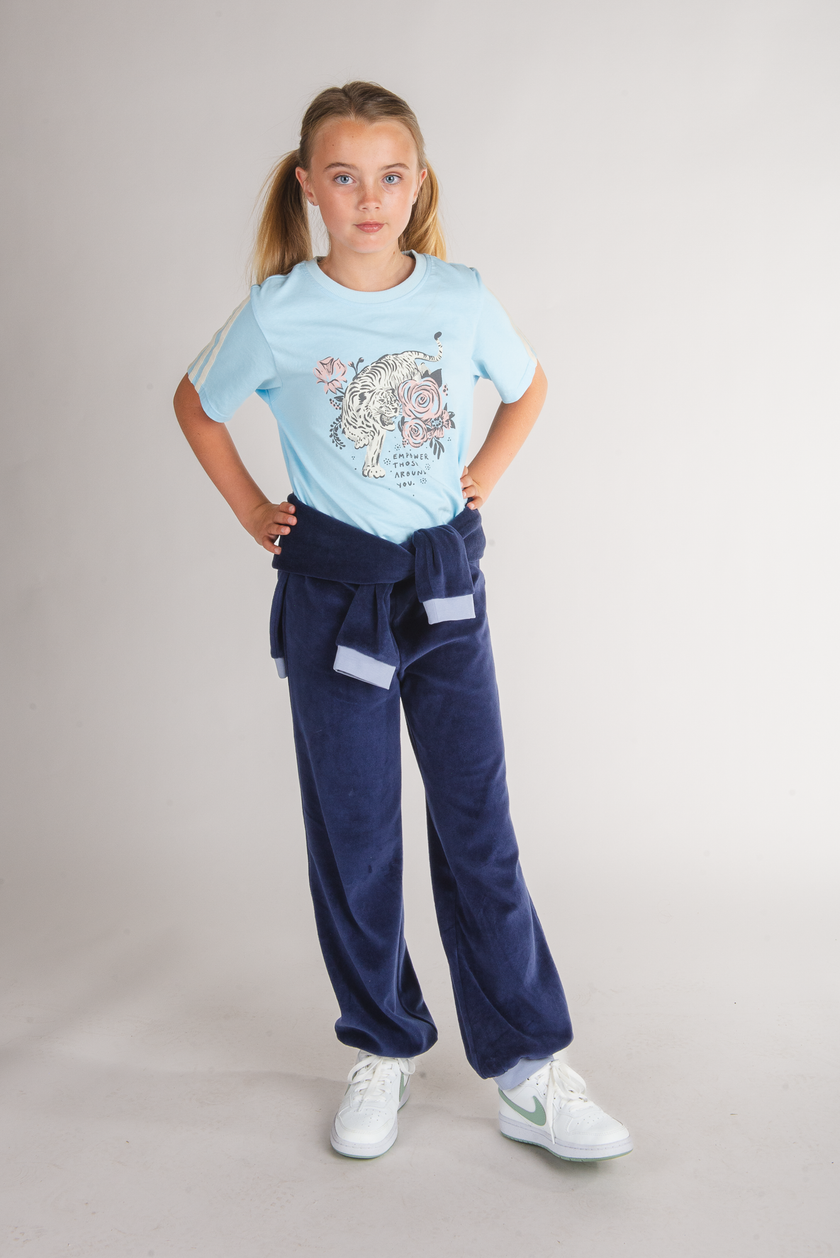 Tween girl wearing a light blue tiger graphic tee with navy sweatpants tied at waist