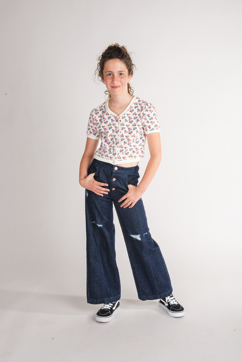 Tween girl wearing dark navy button-front wide-leg jeans with knee rips and floral crop top