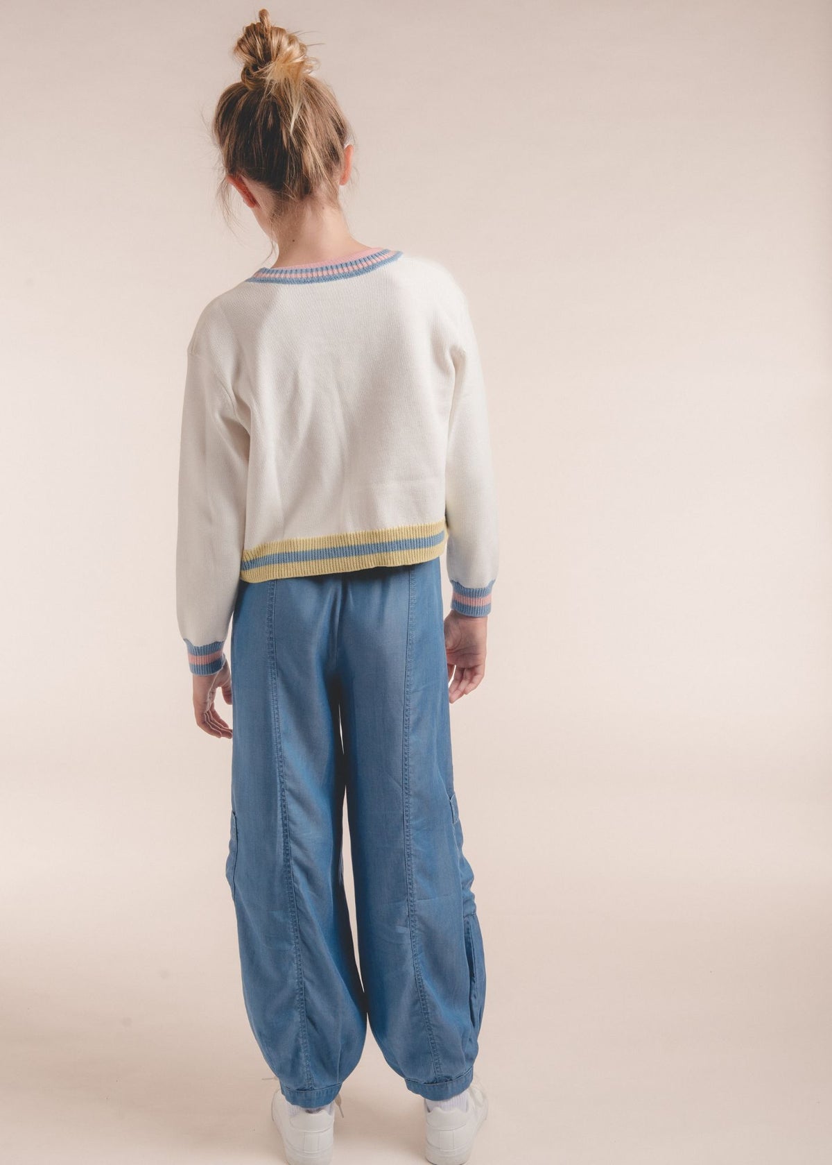 Back view of tween girl wearing blue chambray jogger pants and white striped cardigan