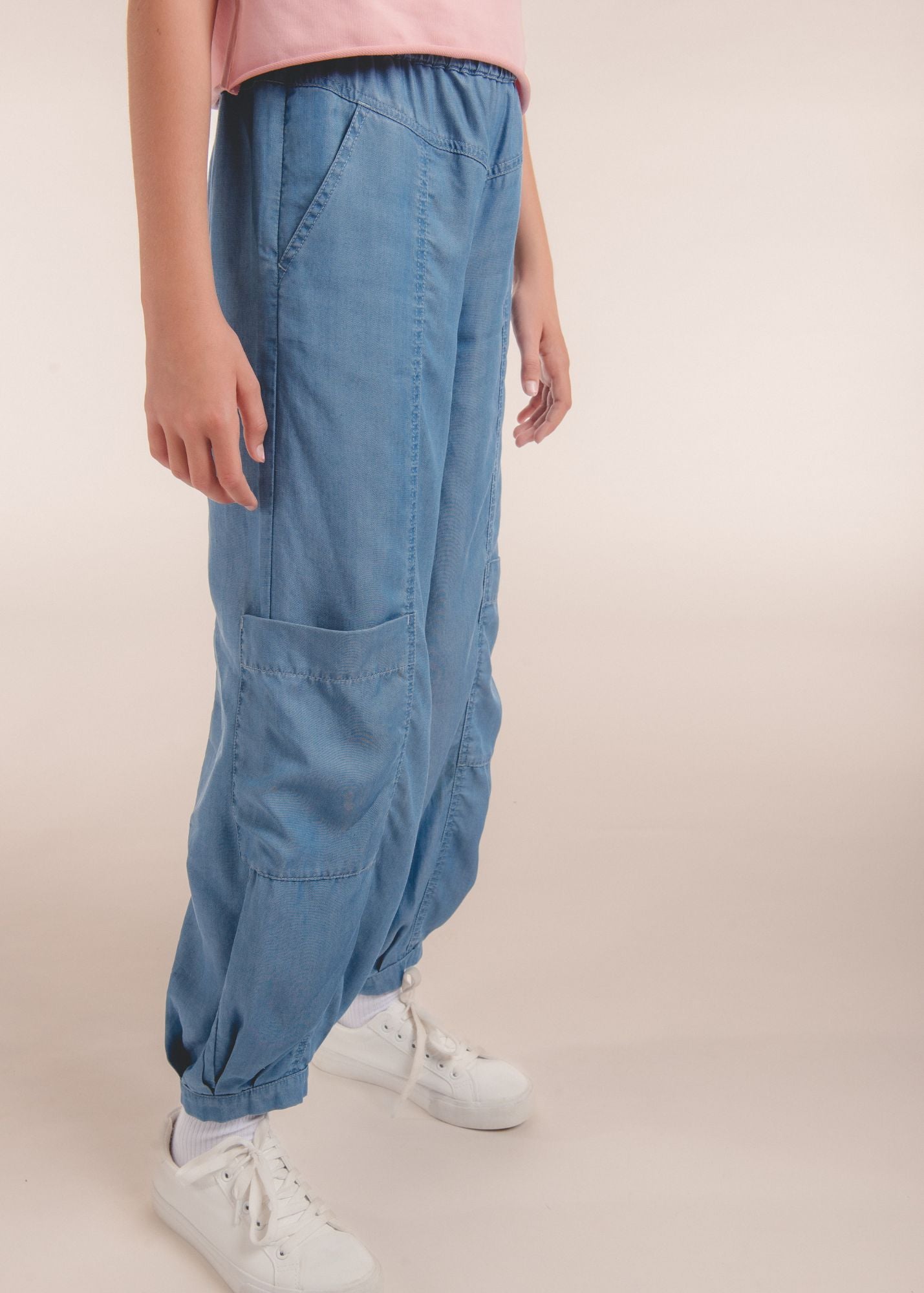 Close-up side view of blue chambray jogger pants with a patch pocket and cuffed ankle