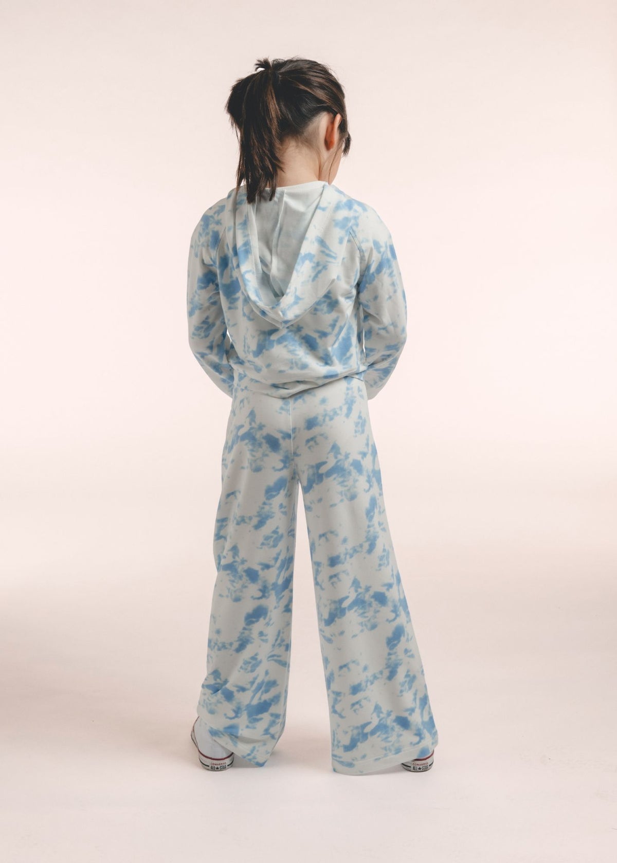 Tween girl wearing blue and white tie-dye wide leg pants and hoodie shown from behind