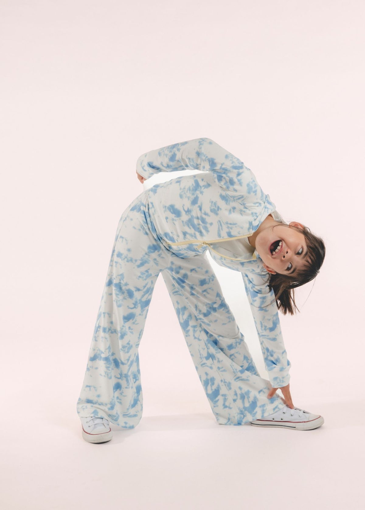 Tween girl wearing blue and white tie-dye wide leg pants bending forward playfully
