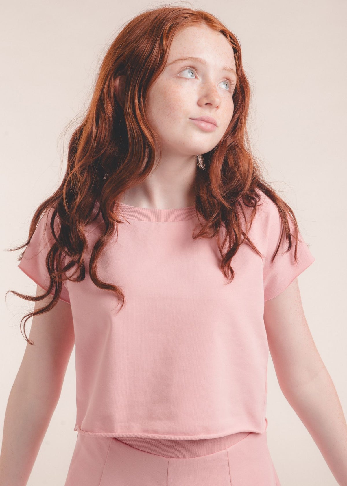 Close-up of tween girl wearing a solid pink crew-neck short-sleeve top