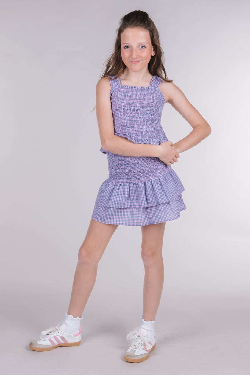 Tween girl wearing a lilac gingham tiered ruffle skirt with a matching smocked top