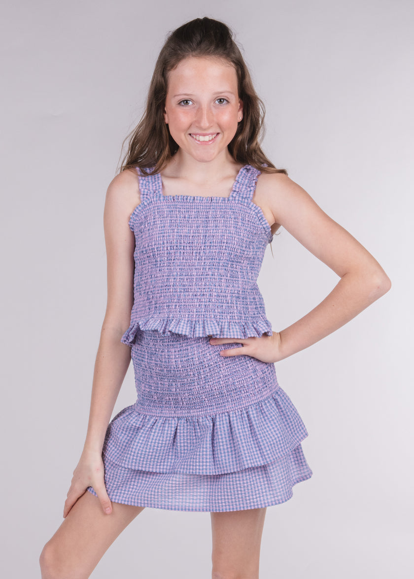 Tween girl wearing a lavender gingham smocked tank top with a matching ruffle skirt