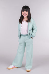 Tween girl wearing seafoam green knit sweater pants with a matching hooded cardigan