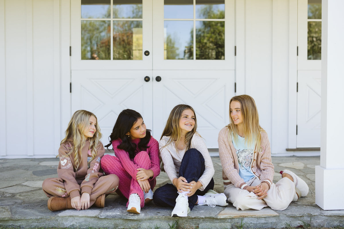 Four girls sitting together on a porch step