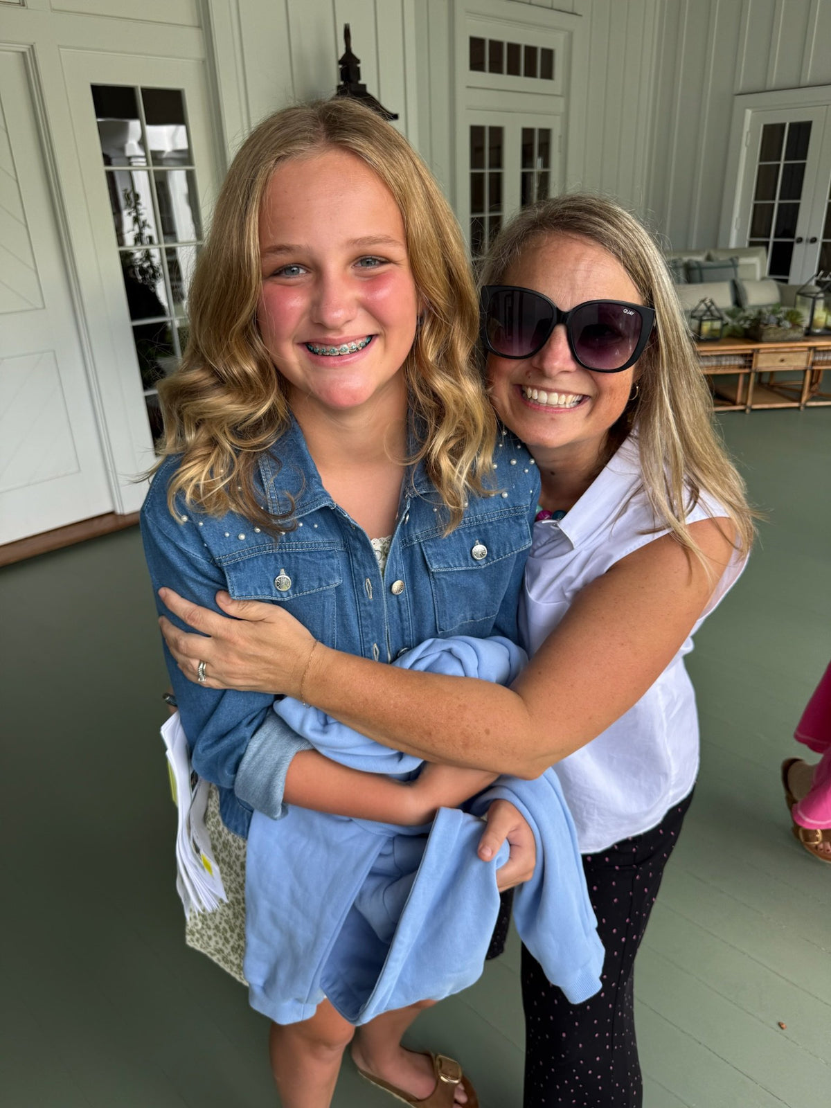 Girl and her mom hugging on a porch