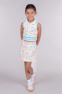 Tween girl wearing a cream floral skort with matching sleeveless zip-front polo top