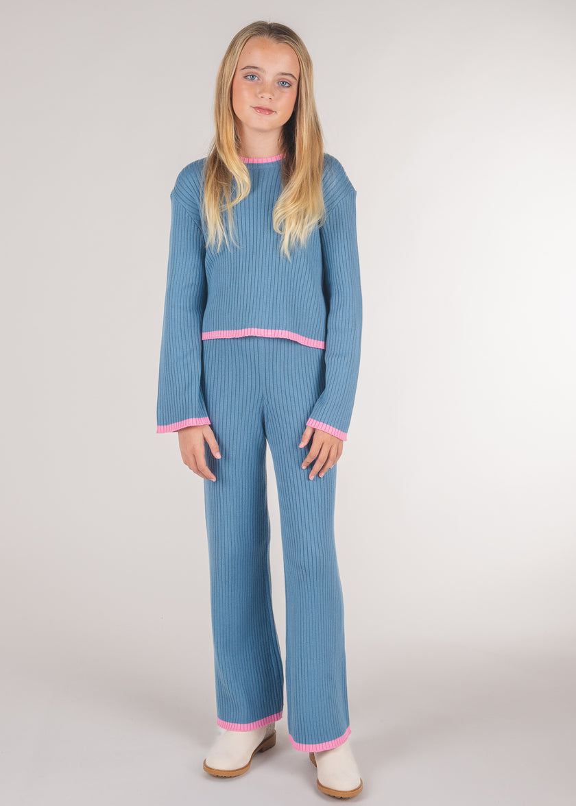 Tween girl wearing blue ribbed knit sweater pants with pink trim and matching sweater