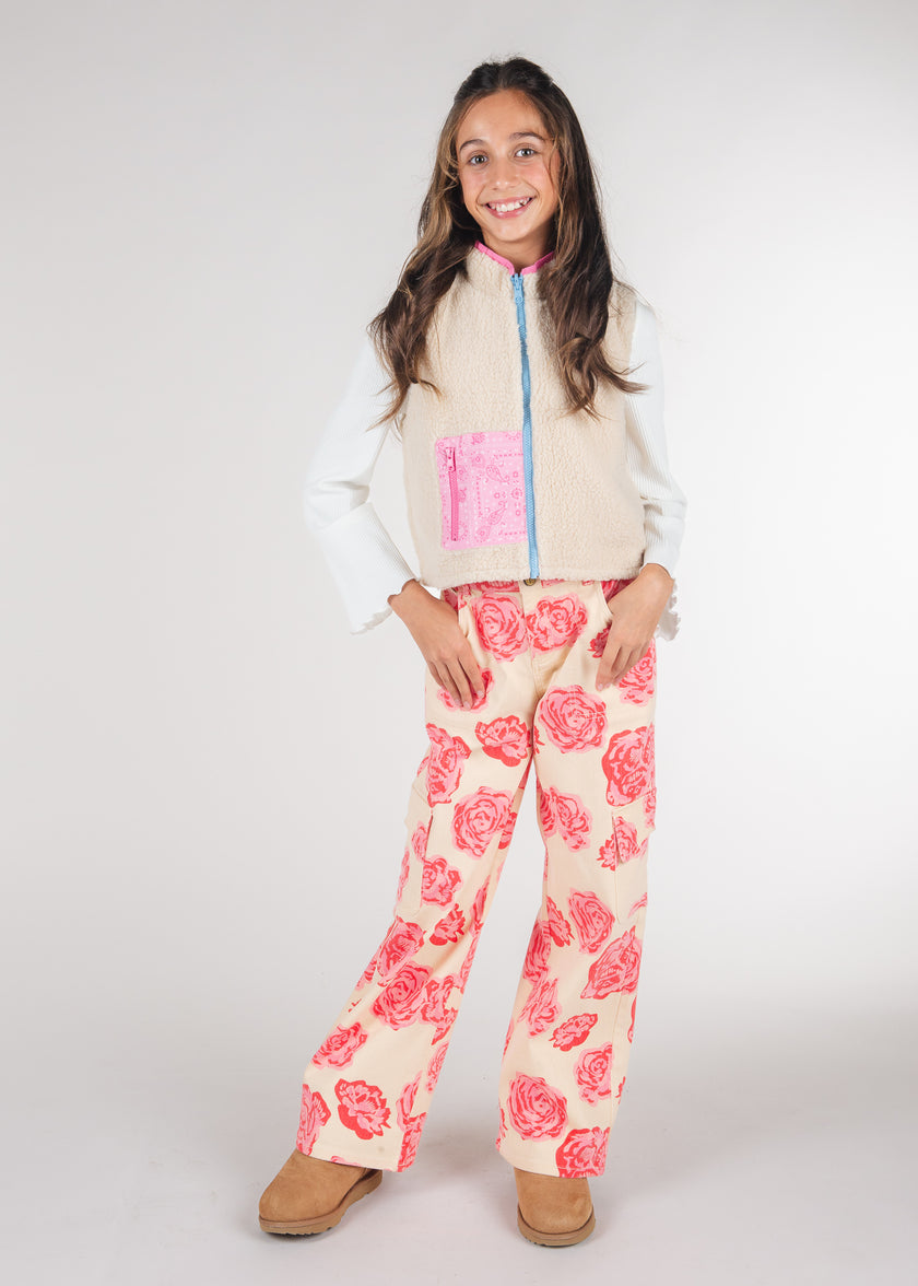 Tween girl wearing ivory sherpa vest with pink bandana print pocket, hands on hips