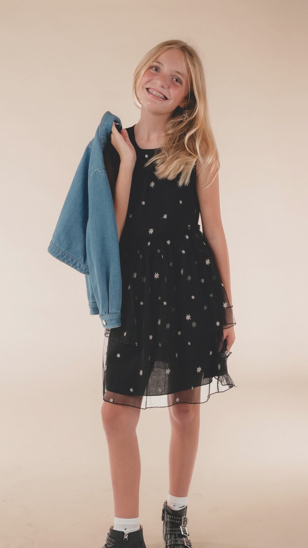 Girl in the Night Sky Dress, a navy dress with small silver stars, holding a denim jacket over her shoulder. Text: She doesn't need more clothes. She needs the right dress for the season.