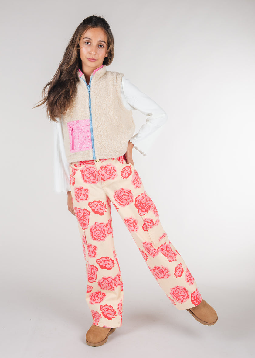 Tween girl wearing cream rose print cargo pants with a cream sherpa vest
